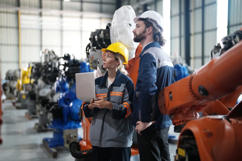 Engineer inspecting automatic AI robot arm and machines in factory. Engineer inspecting automatic AI