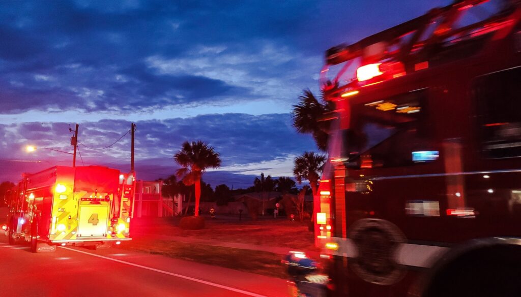Firetrucks responding to a fire alarm pulled at night on roadway flashing red lights.